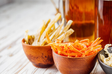 mug of beer and a set of dry fish snacks on a white wooden rustic background