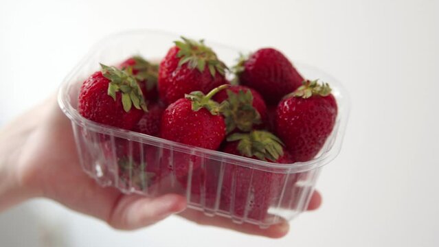Transparent plastic box with fresh strawberries on a white background. 