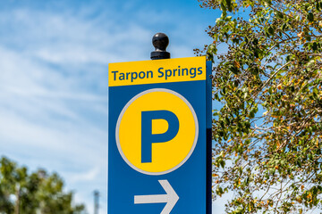 Tarpon Springs, Florida Greek town sign on road street for parking lot closeup with blue sky background and yellow colors