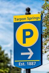 Tarpon Springs, Florida Greek town sign on road street for parking lot closeup with blue sky background and yellow colors vertical view with estimated founding date