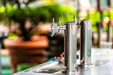 Bavarian village of Helen, Georgia with metal stainless steel beer tap faucet in bier garden garten restaurant during Oktoberfest holiday season closeup with bokeh background outside