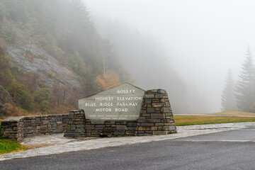 Sign on overlook on Blue Ridge mountains parkway in North Carolina with mist fog on cloudy day and fall colorful foliage for highest elevation at 6053 feet and nobody - obrazy, fototapety, plakaty