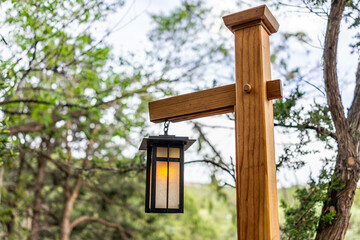 Japanese style garden with illuminated hanging lantern lamp light on wooden pole post in garden...
