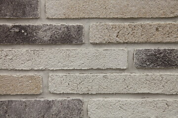 Brick wall with a gray-white porous long brick. Textured background.