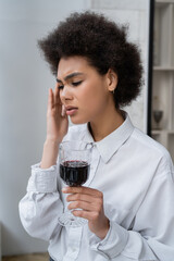 frustrated african american woman holding glass of red wine.