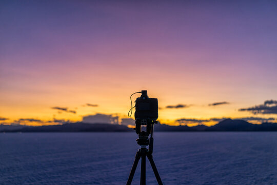 Bonneville Salt Flats near Salt Lake City, Utah at colorful twilight after sunset with purple and yellow sky and tripod with camera doing time lapse photography as pov of photographer