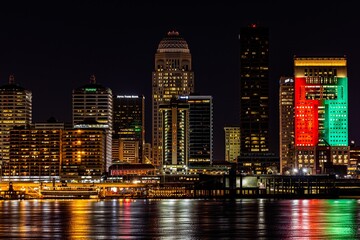 Aerial cityscape of Louisville surrounded by tall buildings near water in night