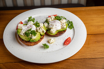 sandwiches with avocado and poached egg on a wooden table in a restaurant
