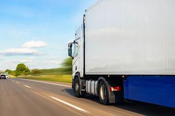 White blank modern delivery big shipment cargo commercial semi trailer truck moving fast on motorway road city urban suburb. Business distribution logistics service. Lorry driving highway sunny day