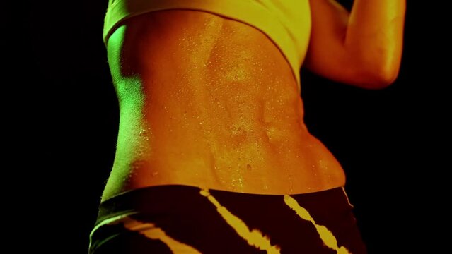 Closeup belly with steel abs of sportive woman training in dark smoky gym in neon light. Sport, action, power, energy concept. Women in sport