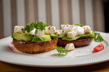 sandwiches with avocado and poached egg on a wooden table in a restaurant
