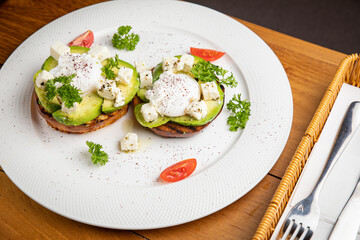 sandwiches with avocado and poached egg on a wooden table in a restaurant
