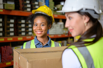 Two girls warehouse workers Help each other lift heavy boxes to move storage.