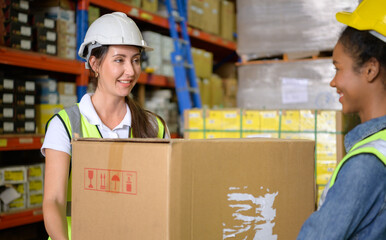 Two girls warehouse workers Help each other lift heavy boxes to move storage.