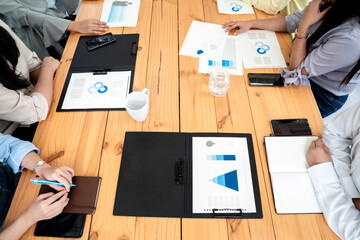 Employees Meeting in conference room. There are triangular diagrams, graphs, and related data set aside on a long brown wooden table.