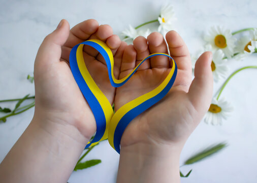 Children's hands hold a blue-yellow ribbon - Powered by Adobe