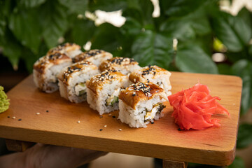 Japanese cuisine. Rolls with sauce on a wooden plate
