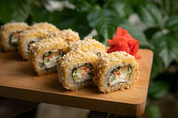 Japanese cuisine. Rolls with sauce on a wooden plate
