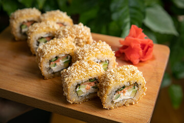 Japanese cuisine. Rolls with sauce on a wooden plate

