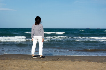 Mujer morena en la playa mirando al horizonte