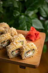 Japanese cuisine. Rolls with sauce on a wooden plate

