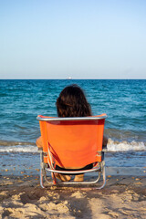 Mujer morena en la playa mirando al horizonte