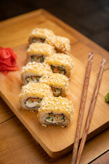 Japanese cuisine. Rolls with sauce on a wooden plate
