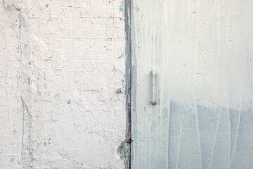 abstract background of metal door in old shabby painted white tiled concrete wall