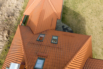 Closeup of attic windows on house roof top covered with ceramic shingles. Tiled covering of building