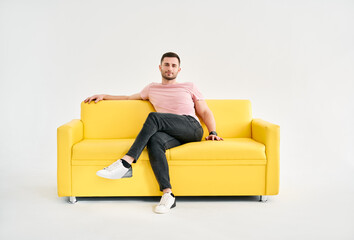 Handsome trendy man posing looking to camera while sitting on comfort sofa