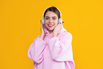 smiling girl listen music in headphones on yellow background