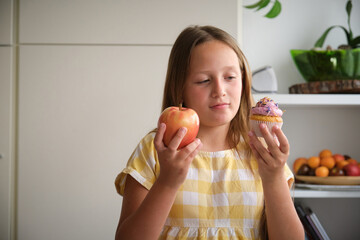 the girl chooses between a cupcake and an apple