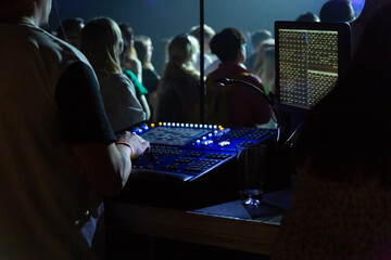 Soundman working on the mixing console in concert hall.