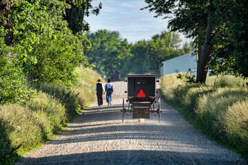 Amish buggy on gravel road with couple walking