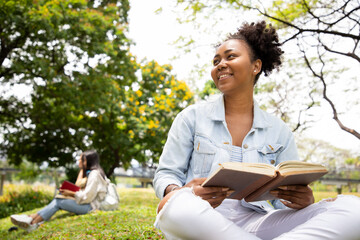 Diversity of a happy female students reading book and looking at natural with bright smiling. Concepts of informal education and learning outside the classroom. Education for all in park