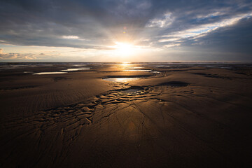 Distinctive dry and wet sand structures during low tide at a beach on Amrum island Germany during scenic sunset on a cloudy calm evening