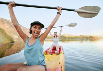 Portrait two diverse young woman cheering and celebrating while canoeing on a lake. Excited friends enjoying rowing and kayaking on a river while on holiday or vacation. Winning on a weekend getaway - obrazy, fototapety, plakaty