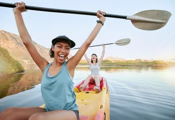 Foto op Canvas Portrait two diverse young woman cheering and celebrating while canoeing on a lake. Excited friends enjoying rowing and kayaking on a river while on holiday or vacation. Winning on a weekend getaway © Jade Maas/peopleimages.com