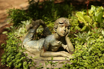 Fototapeta na wymiar Sculpture Of Boy Enjoying A Garden