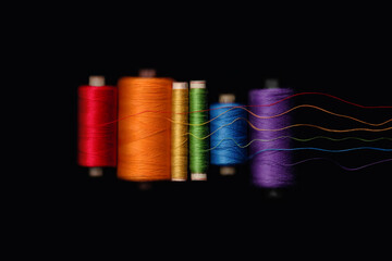 Unwound rainbow skeins of threads of LGBT flag colors isolated on black background. Preparing for a...