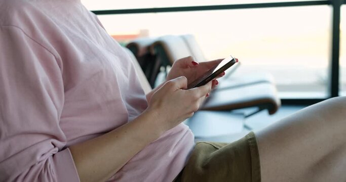 Female hold smartphone while sitting at train station or at airport