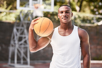 Portrait of a young black male basketball player holding a ball, playing a match on a local sports court outside. One cool muscular man with attitude taking a break to play a fun recreational game - Powered by Adobe