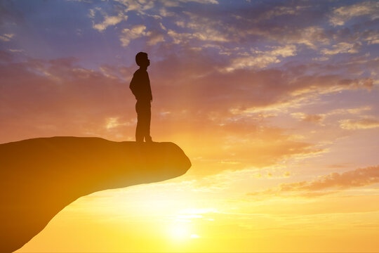 Silhouette of businessman look for the success on top mountain, sky and sun light background.