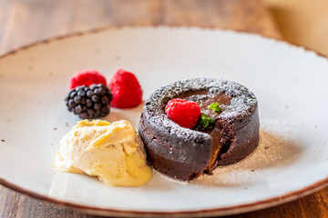Chocolate fondant (cupcake) with raspberries, ice creme and powdered sugar placed on plate