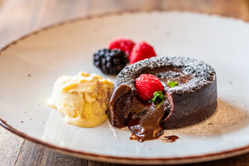 Chocolate fondant (cupcake) with raspberries, ice creme and powdered sugar placed on plate