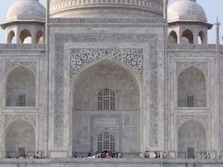 Fototapeta na wymiar Taj Mahal, Agra, India, August 18, 2011: Facade with one of the entrances of the white marble mausoleum with four minarets and large domes. Taj Mahal