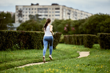 Rear view of woman runner in city park.