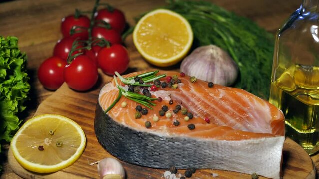 salmon steak.Red fish steak from raw trout with herbs, lemon and olive oil rotates on a wooden board.Healthy food concept. Slow motion