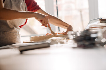 Young hispanic woman wearing apron making pie in kitchen