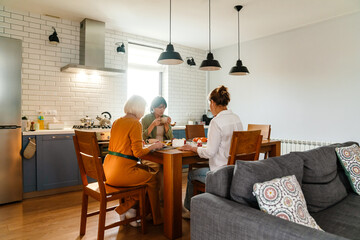 Mature three women talking and drinking tea during birthday lunch